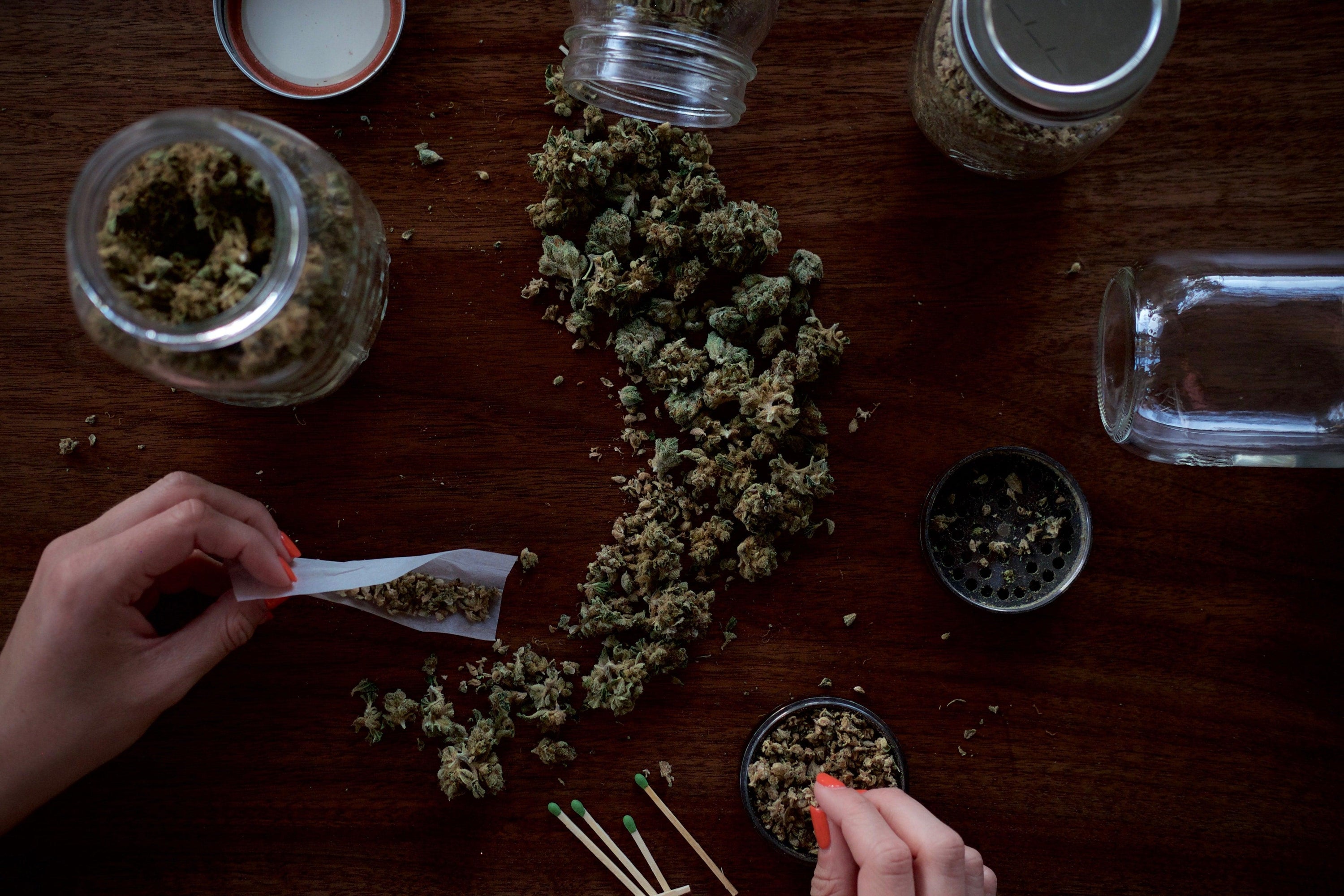 mano vicino a fiori di cannabis e barattoli di vetro